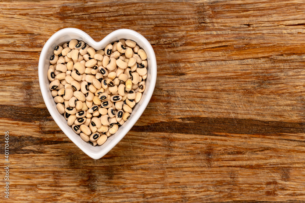 Black eye peas in a heart-shaped bowl background and texture. Top view. Black eye peas in a heart-shaped bowl background and texture. Top view.