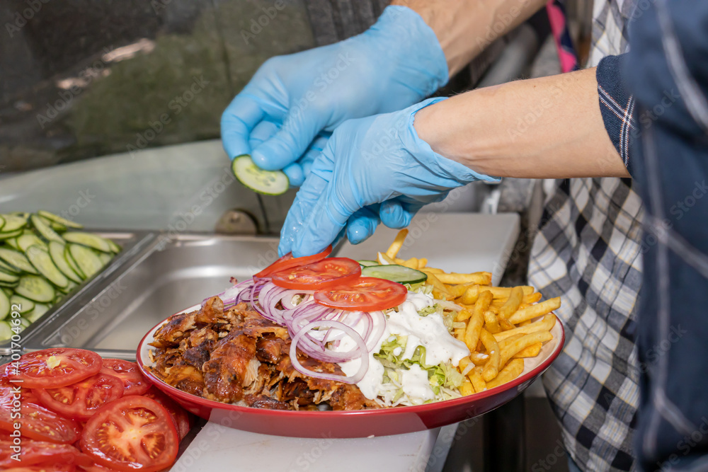 Doner kebab or gyros on a plate with french fries is prepared in the restaurant