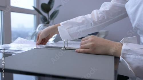 Female hands unlock binder ring, insert file in folder, closes folder
