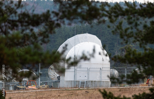 Big satellite dish antennas hidden in green pine tree forest communication center on forest background