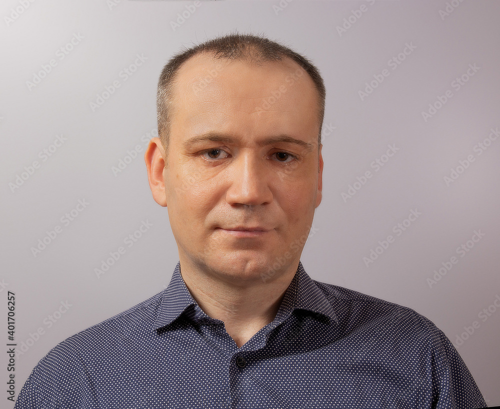 Fototapeta premium Portrait of a mature handsome businessman over gray background. Happy senior European man looking at camera isolated over gray wall with copy space.
