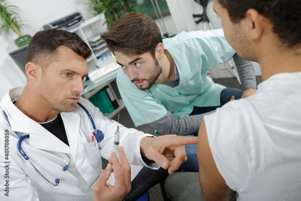 young doctor learning to inject a patient young doctor learning to inject a patient