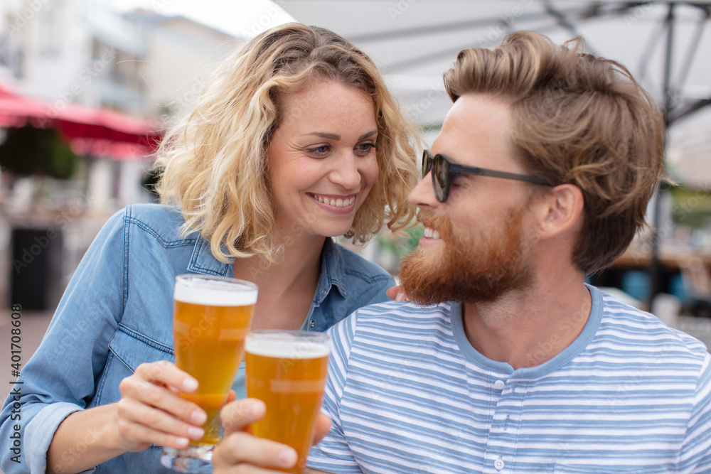happy smiling couple toasting and drinking beer at outdoor pub happy smiling couple toasting and drinking beer at outdoor pub