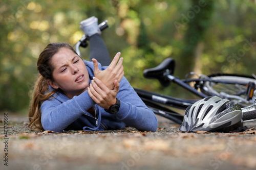 Фотография woman on the ground with wrist injury following bicycle accident