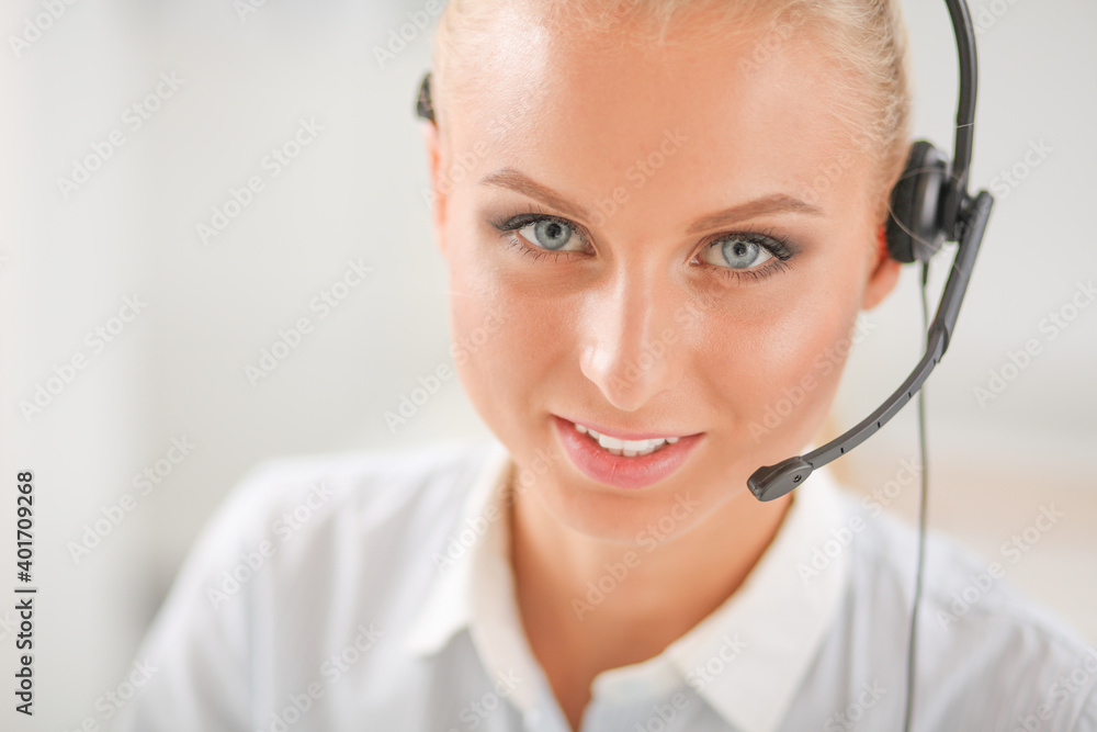 Portrait of pretty young female operator sitting at office desk with headset Portrait of pretty young female operator sitting at office desk with headset