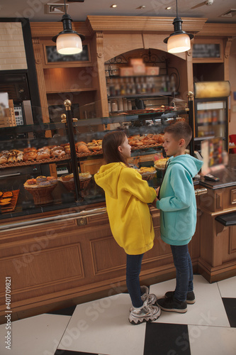 Vertical full length shot of two kids talking, choosing pastry at local bakery shop © Ihor