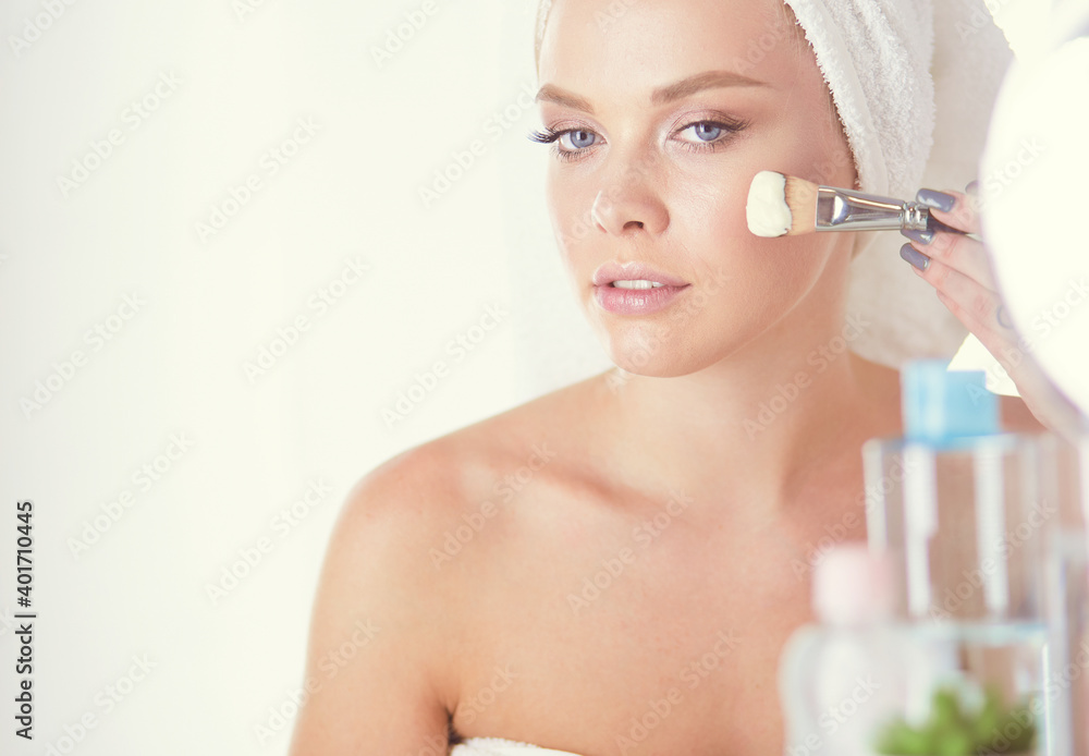 A picture of a young woman applying face powder in the bathroom