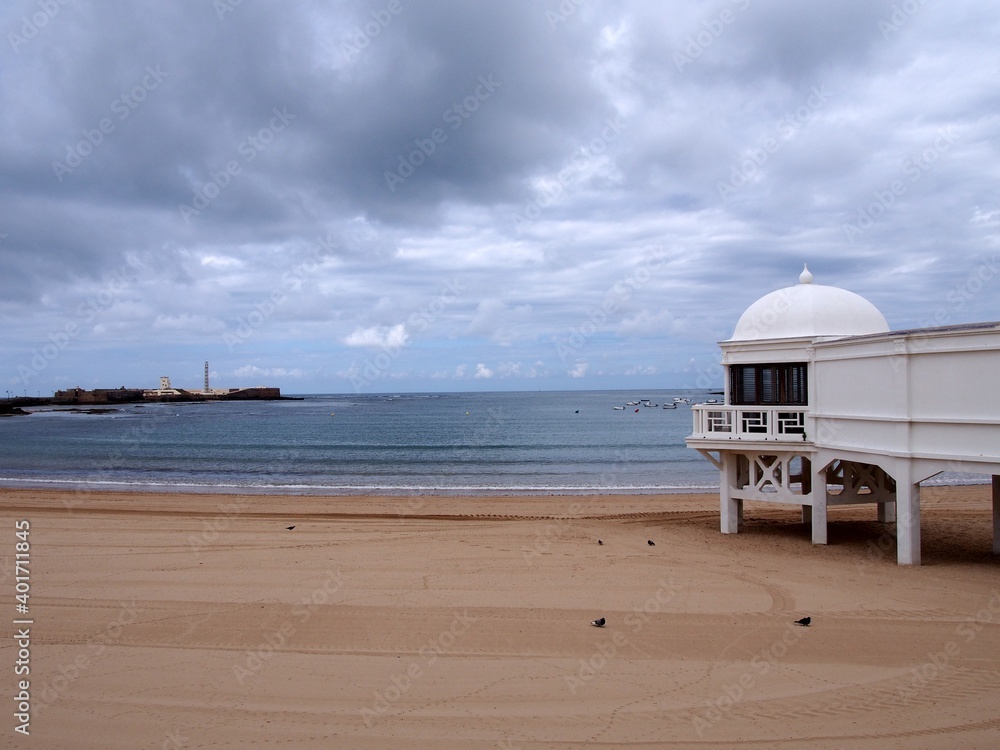 Fototapeta premium Playa of La Caleta, Cadiz, Spa of La Palma in the foreground. In the background, San Sebastian Castle and its lighthouse