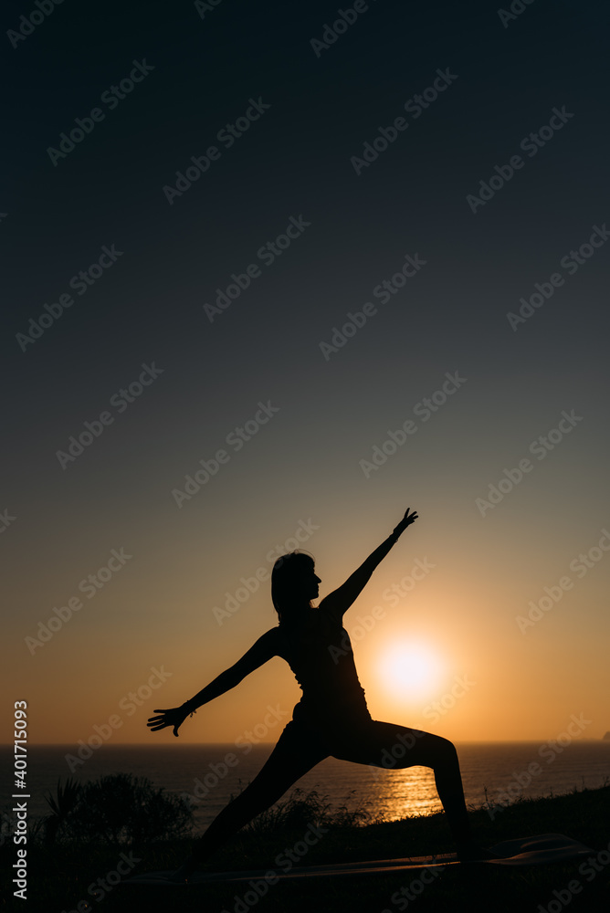 Vertical image of a woman stretching her arms on the shoreline at sunset copy space yoga concept
