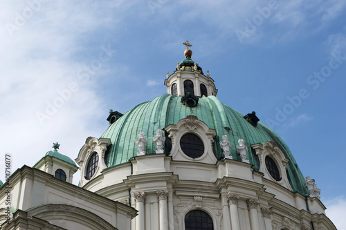 Sunlit green stone dome of the Karlskirche (Rektoratskirche St. Karl Borromäus, or St. Charles Church) in Vienna, Austria. Looking up at the vivid baroque church architecture against a blue sky photo
