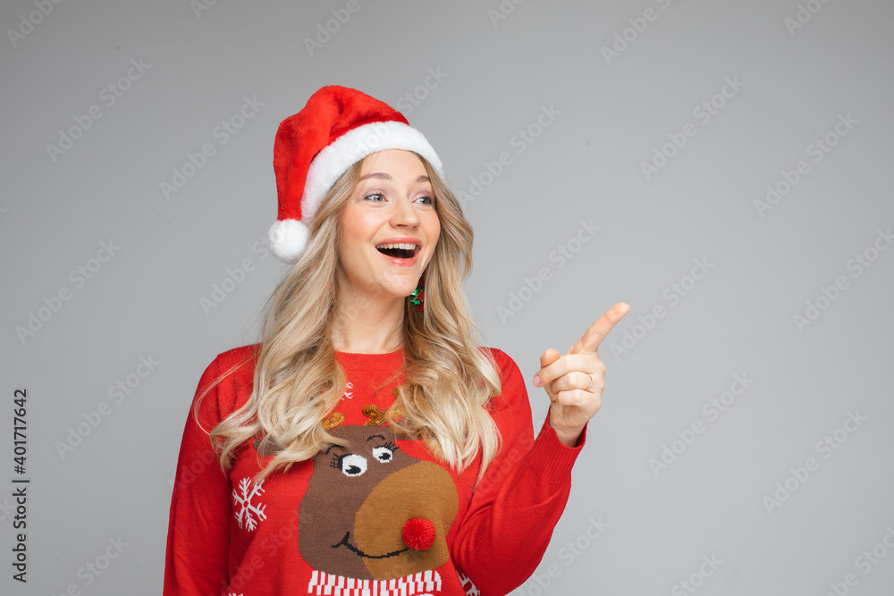 portrait of young woman in sweater and cristmas hat poits to something aside, picture isolated on white background portrait of young woman in sweater and cristmas hat poits to something aside, picture isolated on white background