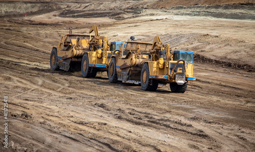 Heavy earthmoving equipment including scapers and motor graders involved in grading operations at a construction site