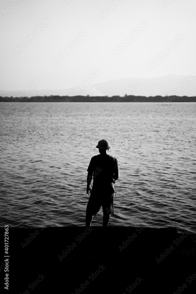 A man standing on the lakeside. 