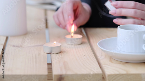 womens hand lighting the candle. selective focus. Cozy flatlay with wooden tray, cup of coffee or cocoa