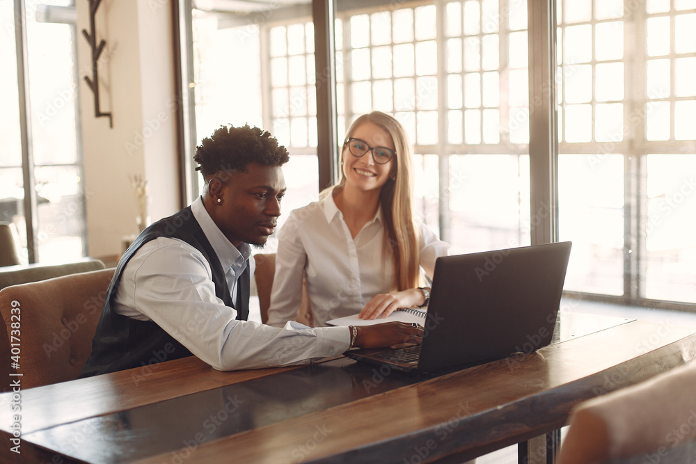 Obraz premium Handsome black man in a blue shirt. Businessman working in a cafe. Woman with her business partner.