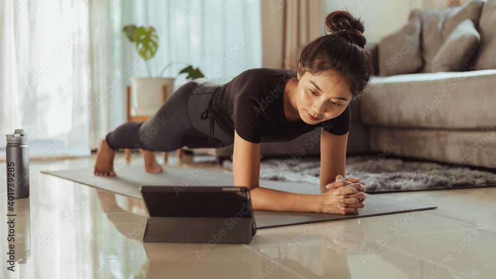 Fit woman doing yoga plank and watching online yoga class. young woman exercising at home. Fit woman doing yoga plank and watching online yoga class. young woman exercising at home.