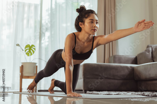 Young woman practicing yoga at home. Fit woman in sportwear doing yoga online at home in living room.