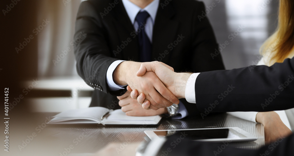 Unknown businessmen shaking hands above the glass desk in a modern office, close-up. Unknown business people at meeting. Teamwork, partnership and handshake concept Unknown businessmen shaking hands above the glass desk in a modern office, close-up. Unknown business people at meeting. Teamwork, partnership and handshake concept