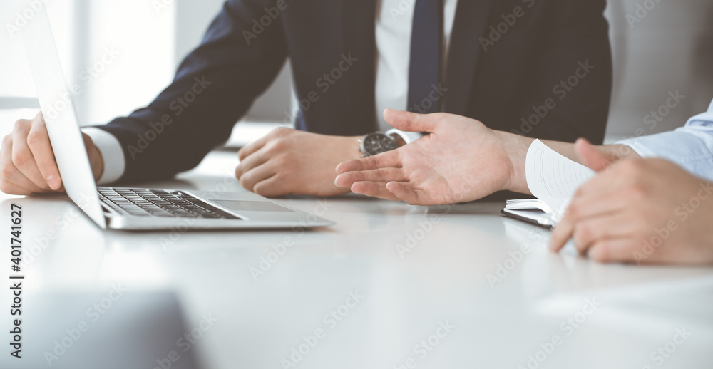 Unknown business people using laptop computer at the desk in modern office. Businessman or male entrepreneur is working with his colleague. Teamwork and partnership concept Unknown business people using laptop computer at the desk in modern office. Businessman or male entrepreneur is working with his colleague. Teamwork and partnership concept