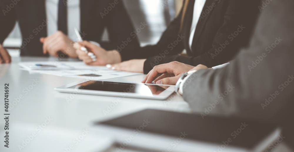 Unknown businessmen and woman sitting, working and discussing questions at meeting in modern office, close-up Unknown businessmen and woman sitting, working and discussing questions at meeting in modern office, close-up