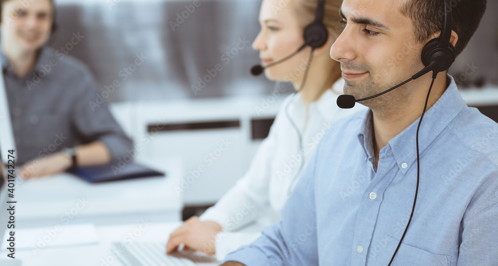 Call center. Group of casual dressed operators at work. Adult businessman in headset at customer service office. Telesales in business Call center. Group of casual dressed operators at work. Adult businessman in headset at customer service office. Telesales in business