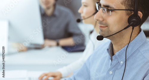 Call center. Group of casual dressed operators at work. Adult businessman in headset at customer service office. Telesales in business