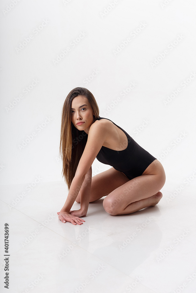 sexy asian woman with long hair posing in black lingerie on white studio background with bare feet. attractive female sitting on floor with her knees bent. model tests of skinny lady in bodysuit sexy asian woman with long hair posing in black lingerie on white studio background with bare feet. attractive female sitting on floor with her knees bent. model tests of skinny lady in bodysuit