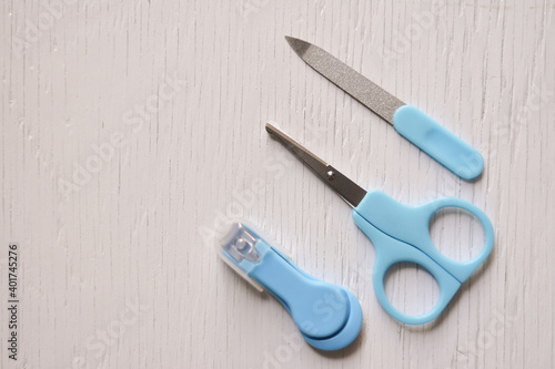 Scissors, clipper and soother on light white table. White color background. Simple tools for baby nail cutting. Empty place for text. Closeup.