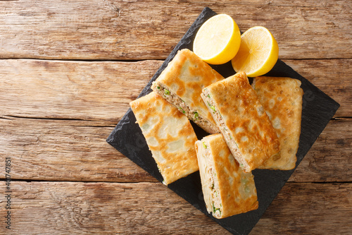 Tasty Mutabbaq Middle Eastern folded pan-fried flatbreads, stuffed with lightly spiced mince meat and egg closeup in the board on the table. horizontal top view above photo