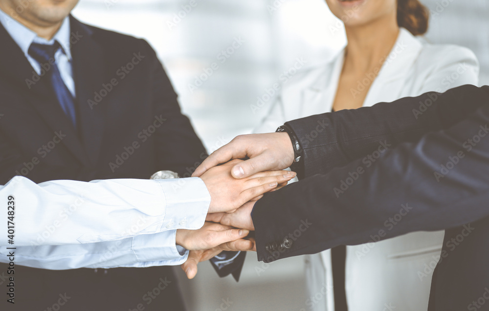 Group of unknown businesspeople are joining hands in a modern office. Unknown businessmen are making circle with their hands. Concept of trust and support in a business