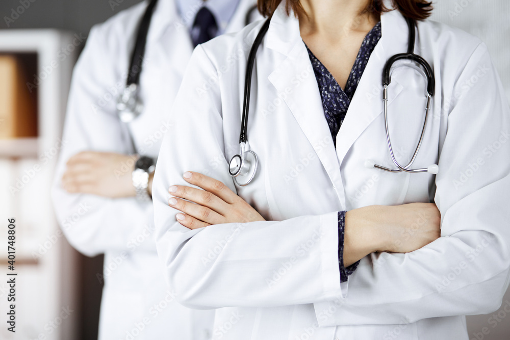 Group of modern doctors standing as a team with arms crossed in sunny hospital and ready to help patients. Medical help, insurance in health care Group of modern doctors standing as a team with arms crossed in sunny hospital and ready to help patients. Medical help, insurance in health care