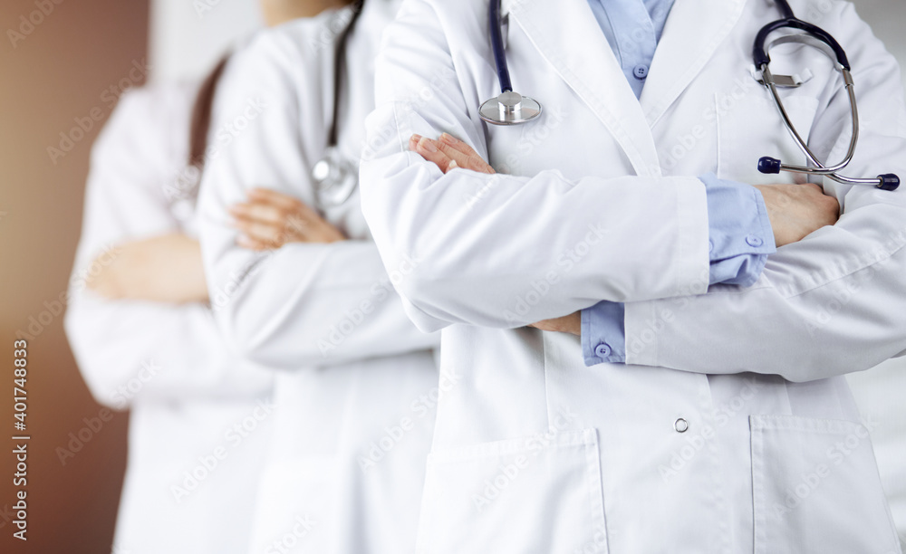Group of modern doctors standing as a team with arms crossed in sunny hospital and ready to help patients. Medical help, insurance in health care Group of modern doctors standing as a team with arms crossed in sunny hospital and ready to help patients. Medical help, insurance in health care
