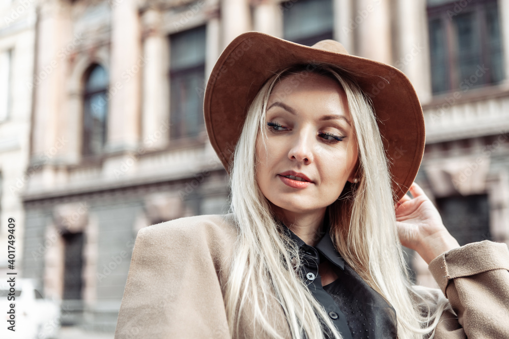 Dramatic portrait of a fashionable woman in an autumn coat and hat on urban architecture background Dramatic portrait of a fashionable woman in an autumn coat and hat on urban architecture background