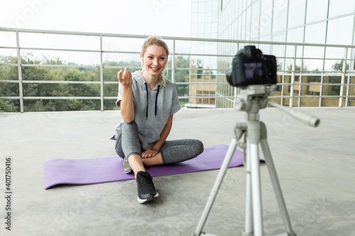 Fitness blogging. Young healthy sports woman recording herself on camera with tripod on rooftop of building, urban style. Vlogging