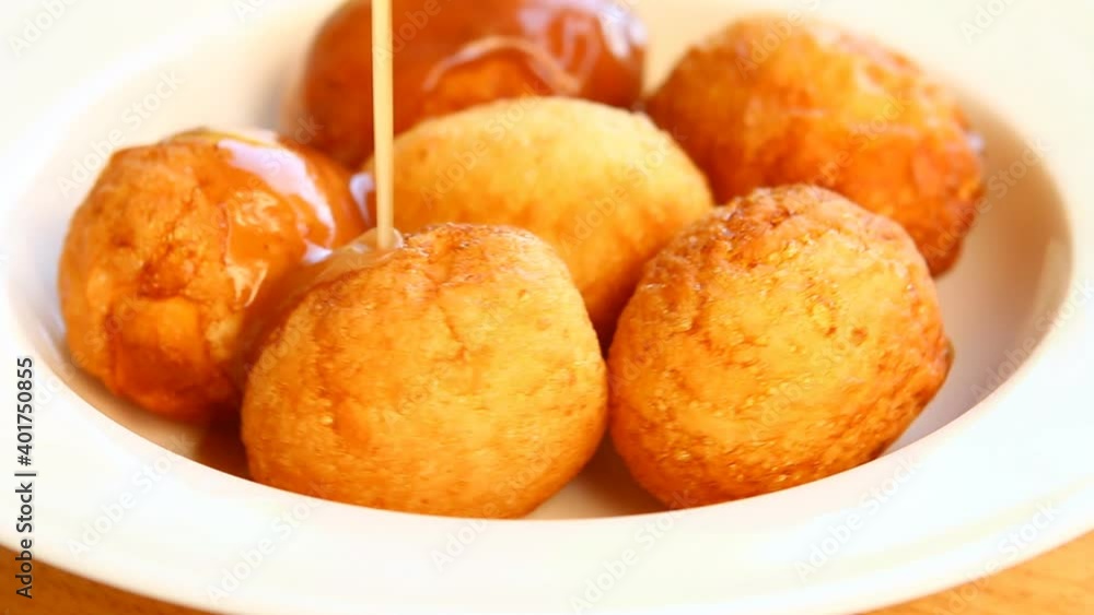 Pouring tamarind sauce on fried hard boiled eggs or Kai Lug Kuey , Thai famous food Pouring tamarind sauce on fried hard boiled eggs or Kai Lug Kuey , Thai famous food