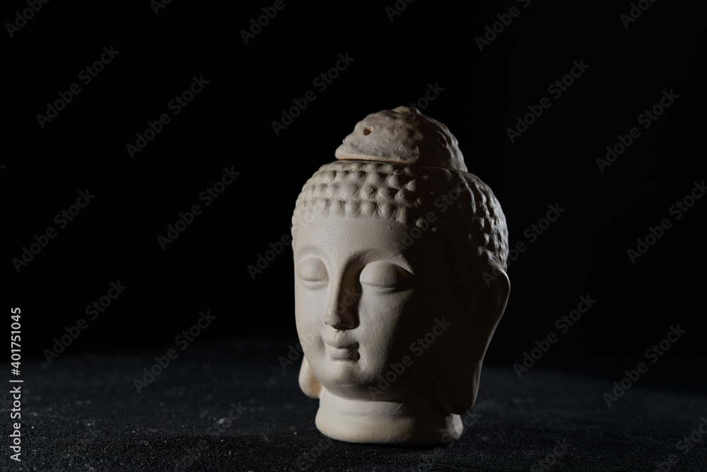 Buddha face, clay aroma lamp on black background Stock Photo Adobe Stock