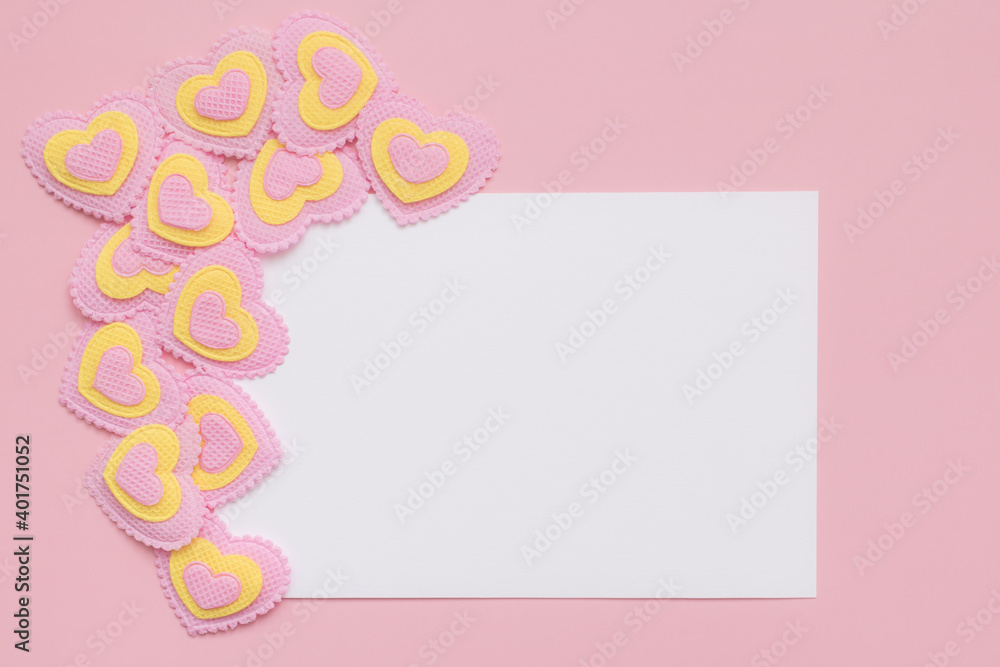 Blank paper white card and pink and yellow hearts on a pink background. Place for text. Flat lay. Top view. Happy Valentines Day.