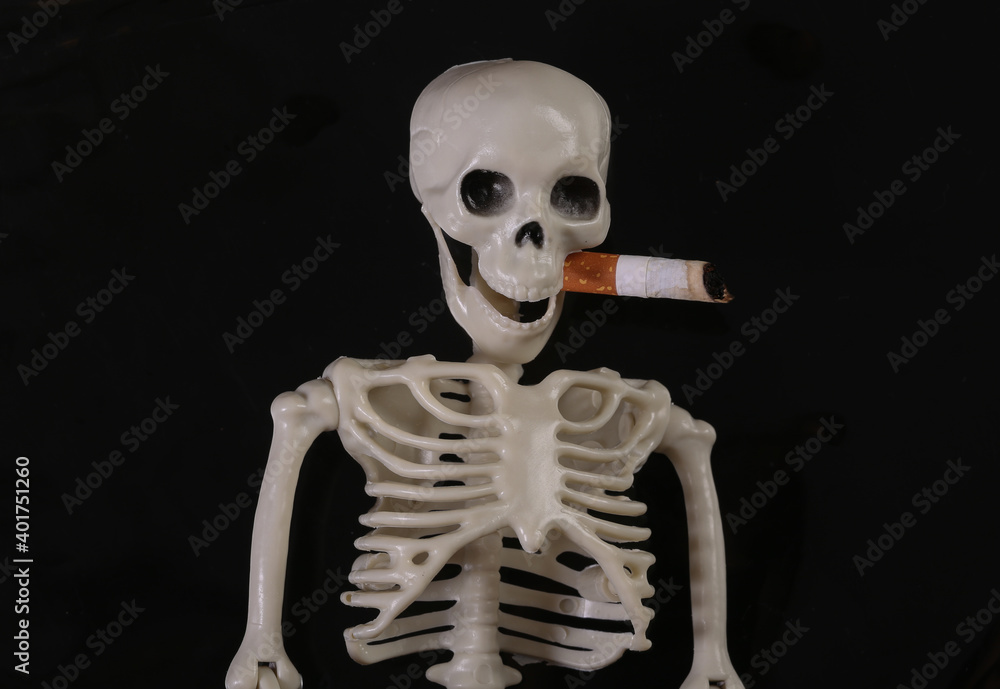 Fake skeleton smoking cigarette isolated on black background Fake skeleton smoking cigarette isolated on black background