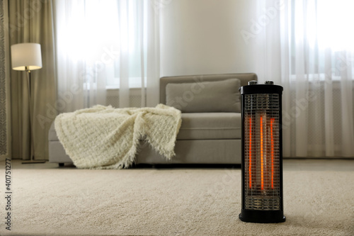 Modern electric halogen heater on floor in living room interior