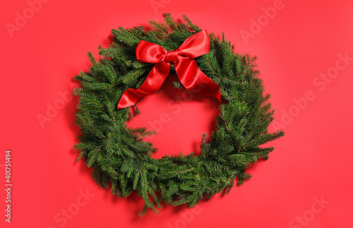 Christmas wreath made of fir branches with bow on red background