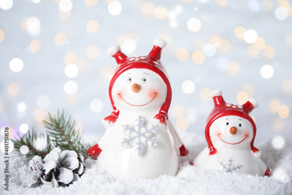 Christmas composition with decorative snowmen on artificial snow against blurred festive lights