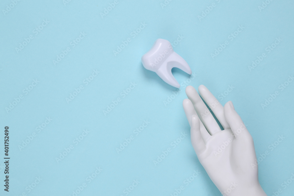 Fake tooth and white hand on blue background. Top view Fake tooth and white hand on blue background. Top view