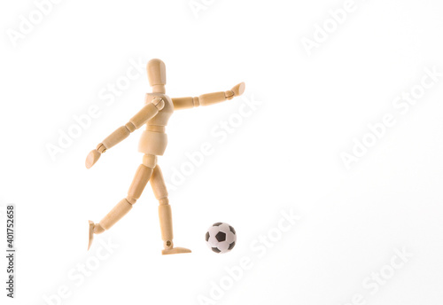 Wooden puppet dummy playing soccer isolated on white background
