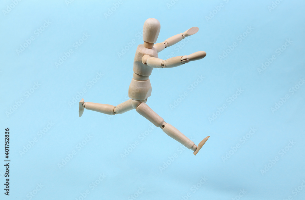 Cheerful wooden puppet jumping on blue background Cheerful wooden puppet jumping on blue background