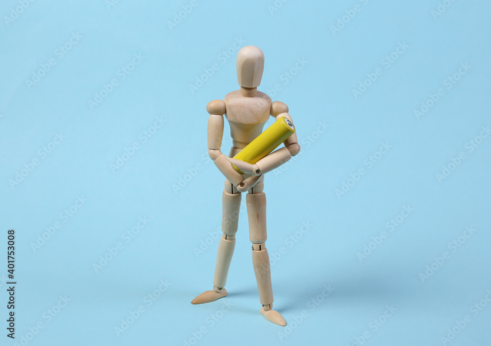 Wooden puppet holding battery on blue background Wooden puppet holding battery on blue background