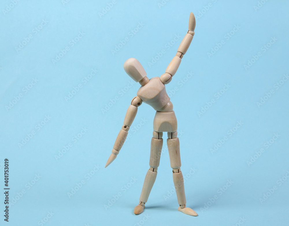 Wooden puppet practicing aerobics on blue background Wooden puppet practicing aerobics on blue background