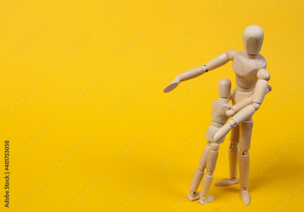 Wooden puppets hug on a yellow background. Parental love concept Wooden puppets hug on a yellow background. Parental love concept