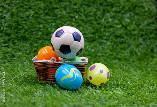 Soccer ball is on easter basket with eggs on green grass