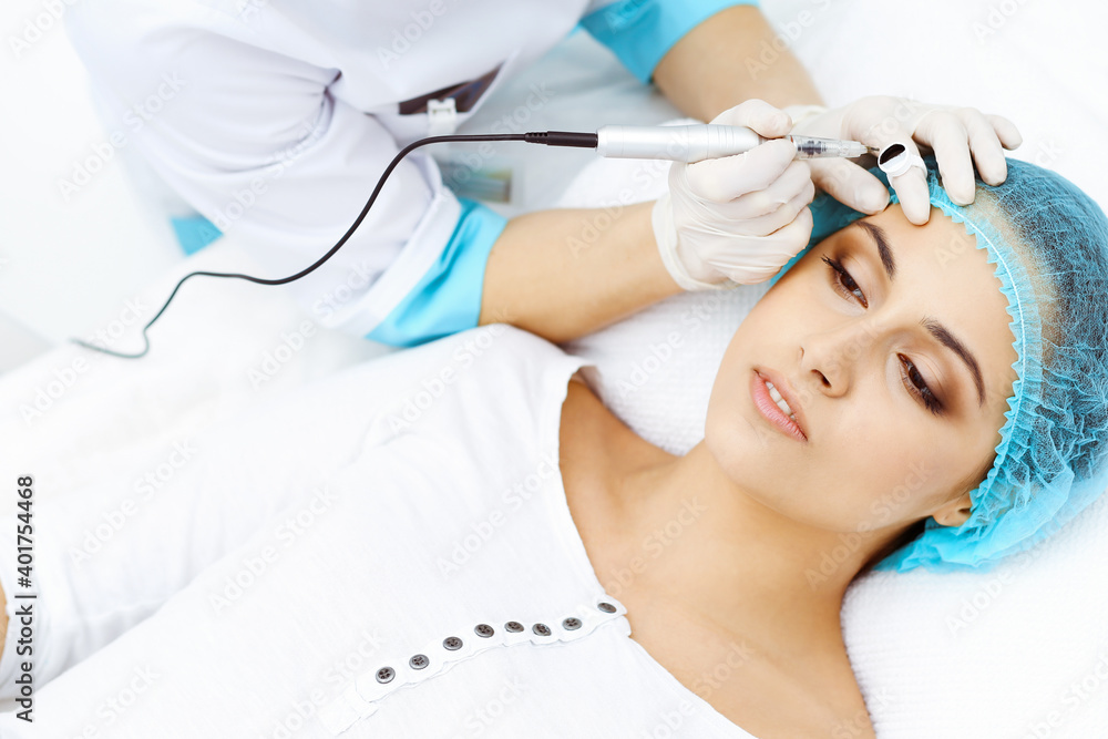 Professional beautician doing eyebrow tattoo at woman face. Permanent brow makeup in beauty salon, closeup. Cosmetology treatment Professional beautician doing eyebrow tattoo at woman face. Permanent brow makeup in beauty salon, closeup. Cosmetology treatment