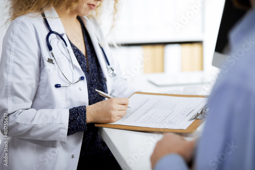 Female doctor and male patient discussing current health examination while sitting in clinic, close-up. Medicine concept